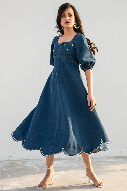 Model posing and looking away from the camera, dressed in our denim ‘Noel Fit & Flare Dress’.