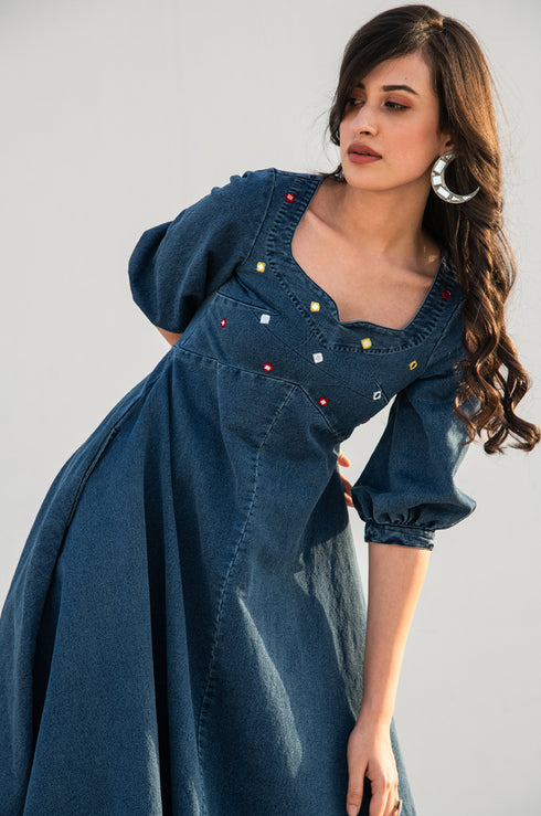 Model posing and looking away from the camera, dressed in our denim ‘Noel Fit & Flare Dress’.