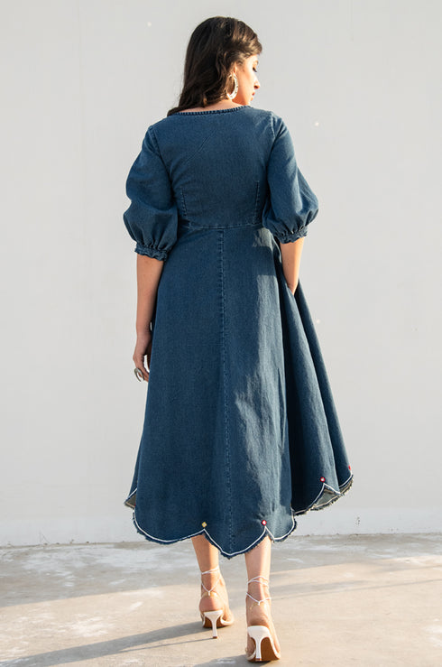 Model posing and looking away from the camera, dressed in our denim ‘Noel Fit & Flare Dress’.