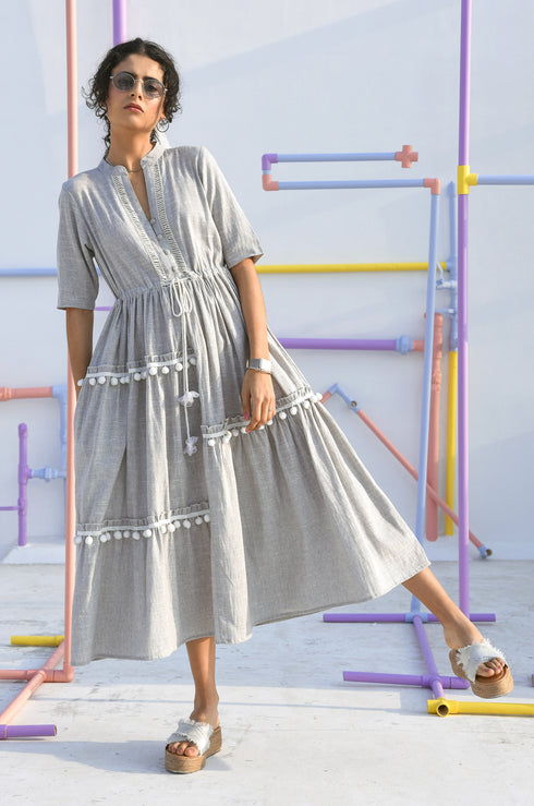 Woman in a grey dress, holding a tote bag.